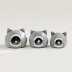 Three gray cat-shaped plush pet houses with ear details and circular openings, arranged in a row on a light beige studio background.