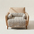A beige upholstered armchair with a cream and black herringbone-patterned throw blanket draped across the seat and back, shown against a plain light beige studio background.