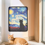 A rectangular wall cat scratcher art piece featuring a stylized cat silhouette against a swirling blue and yellow starry sky, hung on a beige wall above an orange tabby cat lying on a windowsill in an indoor setting.